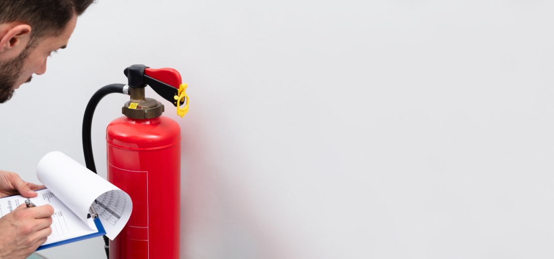 Brandschutzbeauftragter überprüft einen Feuerlöscher - eine seiner Aufgaben