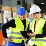 Frau zeigt Mann eine Checkliste über die Arbeitsschutzbestimmungen im Betrieb