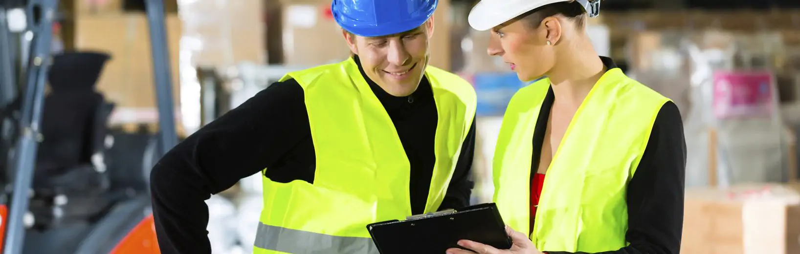 Frau zeigt Mann eine Checkliste über die Arbeitsschutzbestimmungen im Betrieb