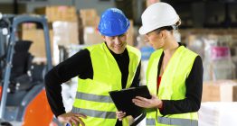 Frau zeigt Mann eine Checkliste über die Arbeitsschutzbestimmungen im Betrieb