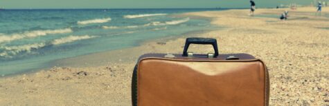 Alter Koffer steht an einem Sandstrand