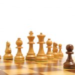 Schwarzer Bauer steht weißen Schachfiguren gegenüber