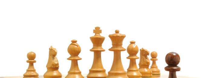 Schwarzer Bauer steht weißen Schachfiguren gegenüber