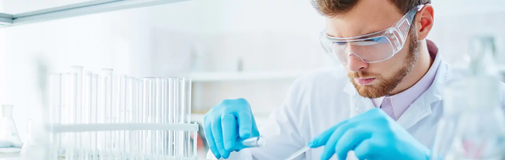 Mann arbeitet mit Gefahrstoffen im Labor - hier müssen die Gefährdungen beurteilt werden und er braucht eine Gefahrstoffunterweisung.