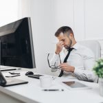 Sicherheit im Büro: Darauf kommt es an Mann reibst sich seine Augen, die vom Blick auf den Bildschirm müde geworden sind