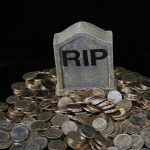 Ein kleiner Grabstein mit der Aufschrift "RIP" steht in einem Haufen Geldmünzen.