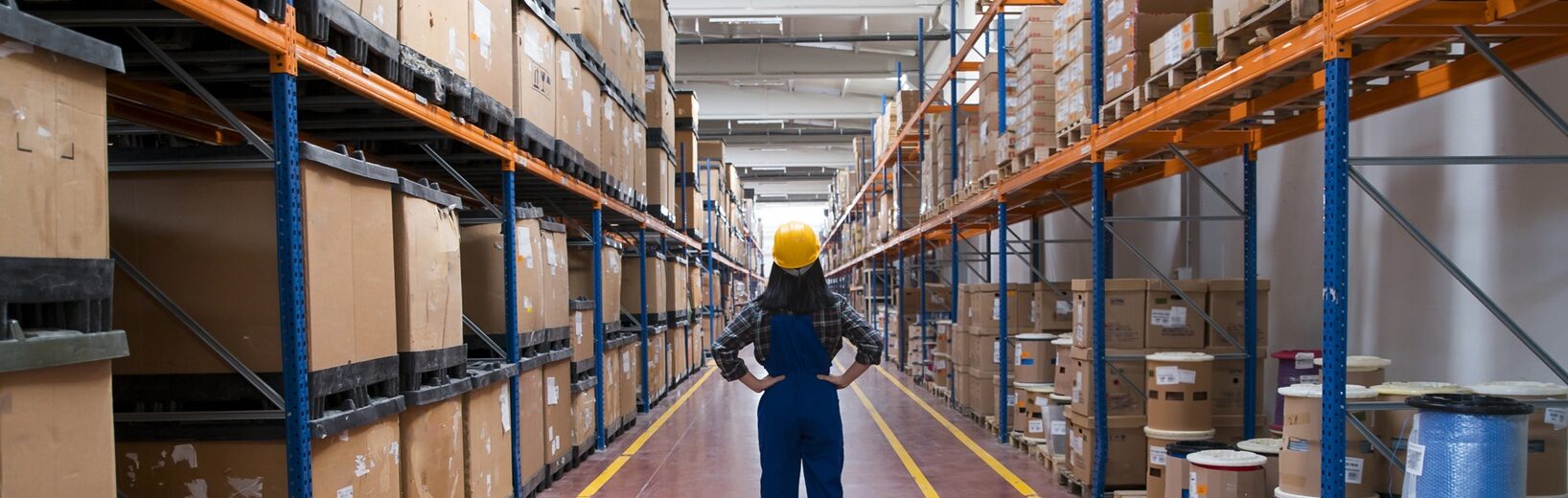 Arbeitssicherheit im Lager Frau steht selbstbewusst in einem Flur in einer Lagerhalle