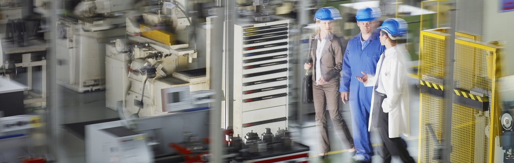 Schutzeinrichtungen Drei Menschen an Maschinen vorbei, die in Schutzeinrichtungen stehen.