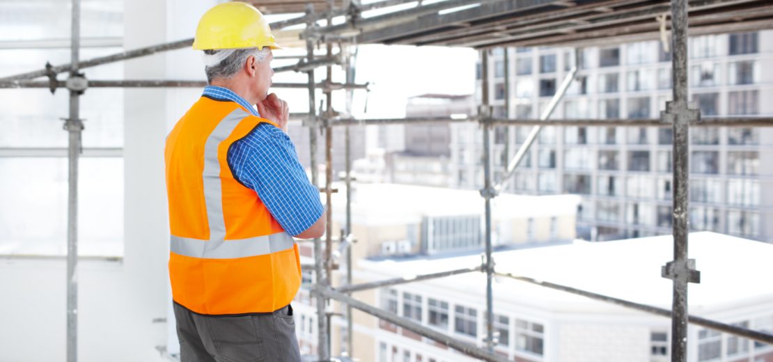 Mann steht beim Arbeiten auf Gerüsten überlegt