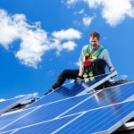 Mann installiert Photovoltaikanlagen mit Absturzsicherung