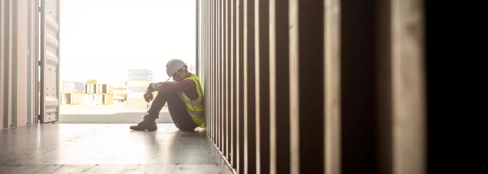 Mitarbeiter sitzt müde und psychisch überlastet in einem Container.