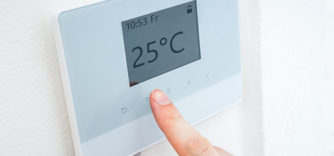 Person passt die Temperatur in der Arbeitsstätte an.