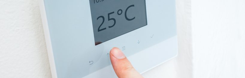 Person passt die Temperatur in der Arbeitsstätte an.
