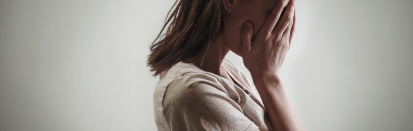 Traumagefahren am Arbeitsplatz wirksam begegnen Frau bedeckt verzweifelt ihr Gesicht mit den Händen