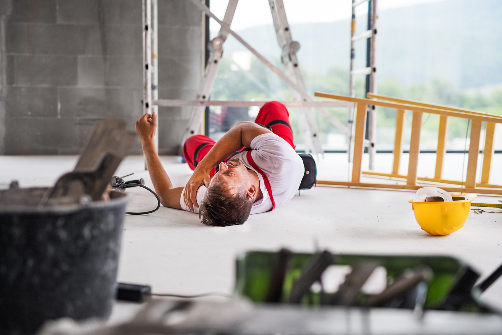 Mann liegt nach einem Arbeitsunfall mit Schmerzen auf dem Boden. Eine Unterweisung in Arbeitsschutz will solche Unfälle verhindern.