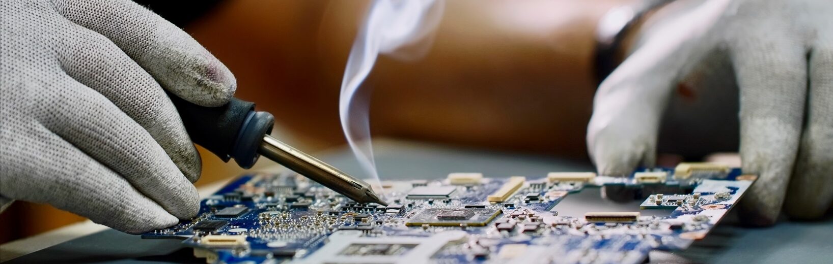 Lötarbeitsplatz Ein Mensch, der etwas an einer Platte lötet