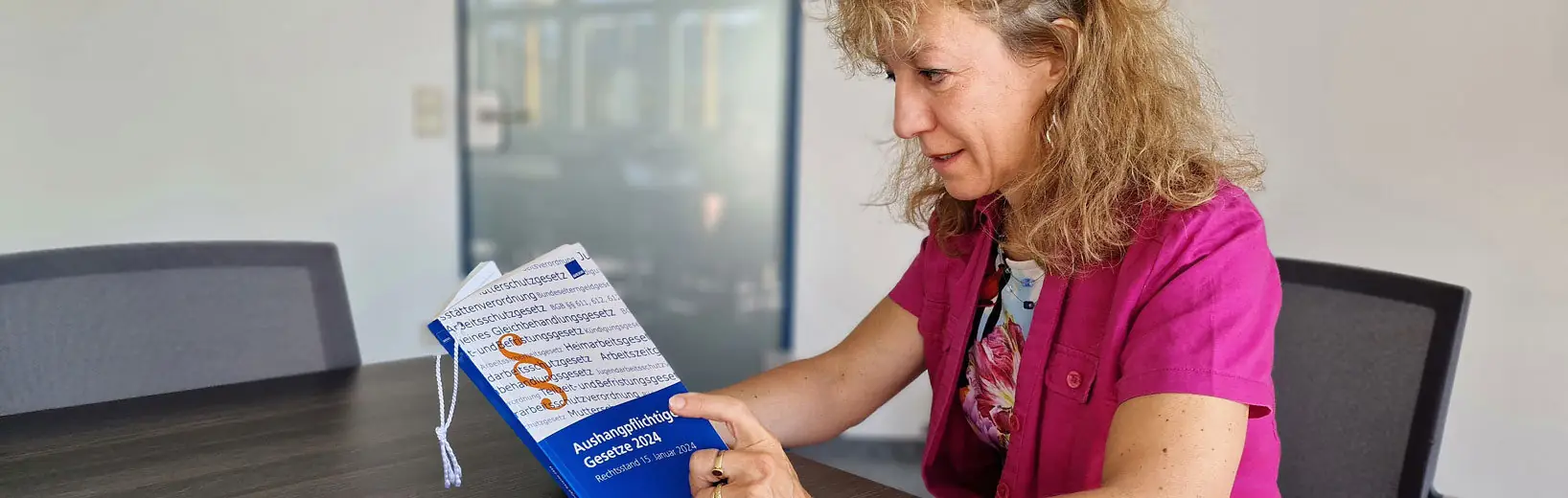 Frau liest in den aushangpflichtigen Gesetzen 2024