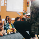 Lehrer liest Grundschulklasse etwas vor.
