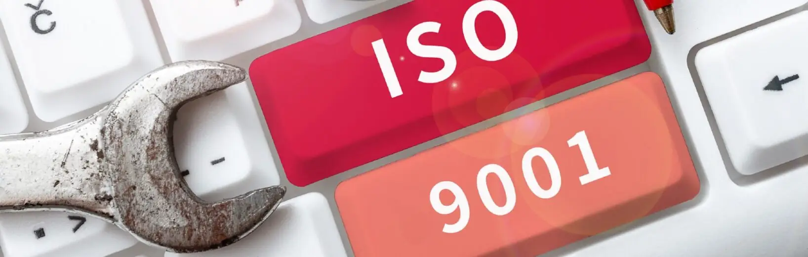 Stand der Revision der ISO 9001 im Dezember 2025 Auf einer PC-Tastatur sind zwei Tasten mit ISO und 9001 beschriftet, daneben liegen zwei unterschiedlich große Schraubenschlüssel