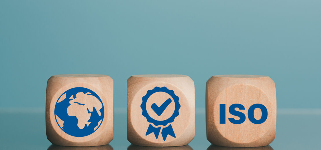 Die Symbole auf den drei Würfeln sollen den Inhalt von Amendment 1 zur ISO 9001 symbolisieren. Zu sehen ist auf dem linken Würfel die Erdkugel, in der Mitte ein Haken in einem Zertifikat und rechts der Schriftzug ISO.