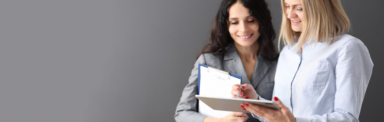 Die Qualifikation interner Auditoren im Blick behalten Eine Geschäftsfrau erläutert einer anderen etwas anhand eines Tablets