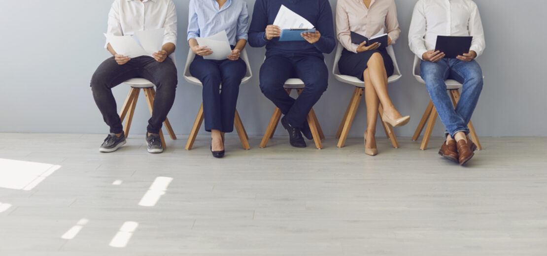 Frauen und Männer sitzen und warten auf ihr Bewerbungsgespräch