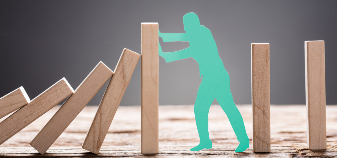 Mann blockiert Domino-Effekt
