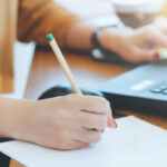 Hand mit Stift macht Notizen auf einem Blatt Termin