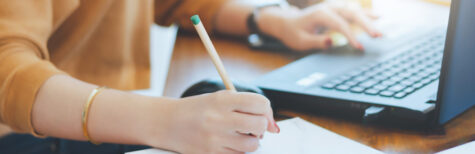 Hand mit Stift macht Notizen auf einem Blatt Termin