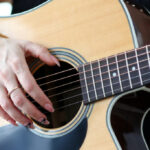 Musiklehrer spielt Gitarre, Nahaufnahme einer Frauenhand