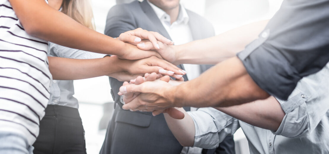 Leute legen Hände übereinander als Zeichen der Verbundenheit und Solidarität