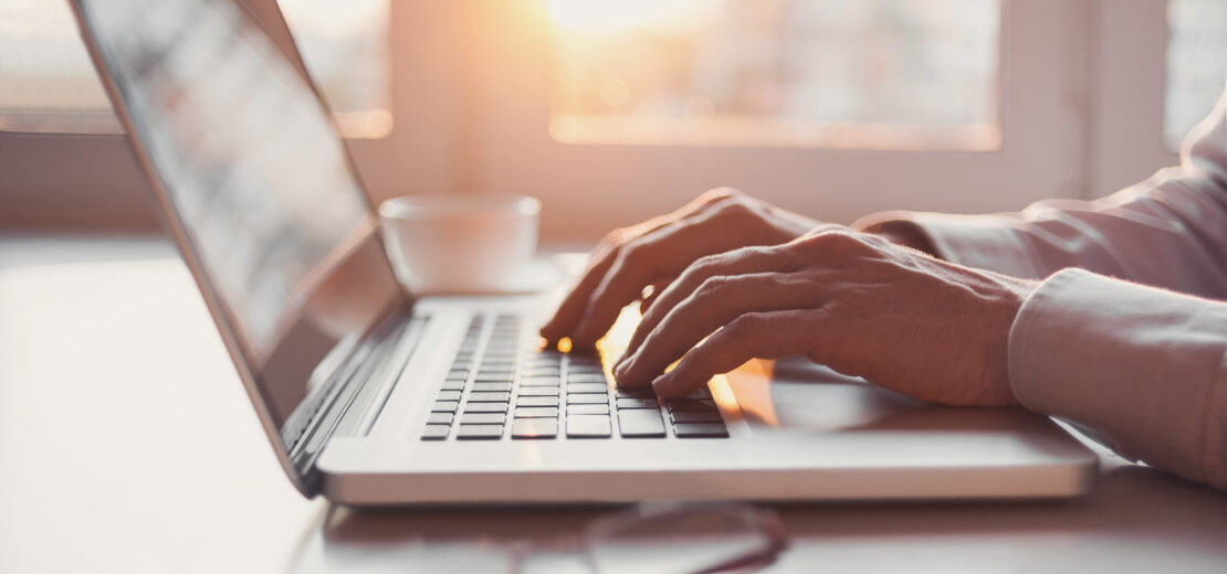 Person tippt auf Notebook-Tastatur