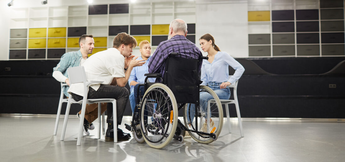 Mann im Rollstuhl sitzt mit anderen Personen im Stuhlkreis