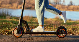 Junge Frau fährt mit dem E-Scooter, Nahaufnahme von Bein und Turnschuh