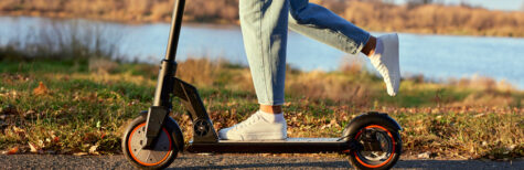 Junge Frau fährt mit dem E-Scooter, Nahaufnahme von Bein und Turnschuh
