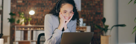 Frau im Homeoffice hat Online-Meeting und sitzt mit Headset vor dem Laptop