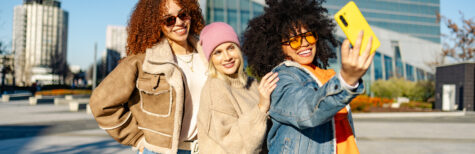 drei glückliche junge Frauen, die in der Stadt ein Selfie machen