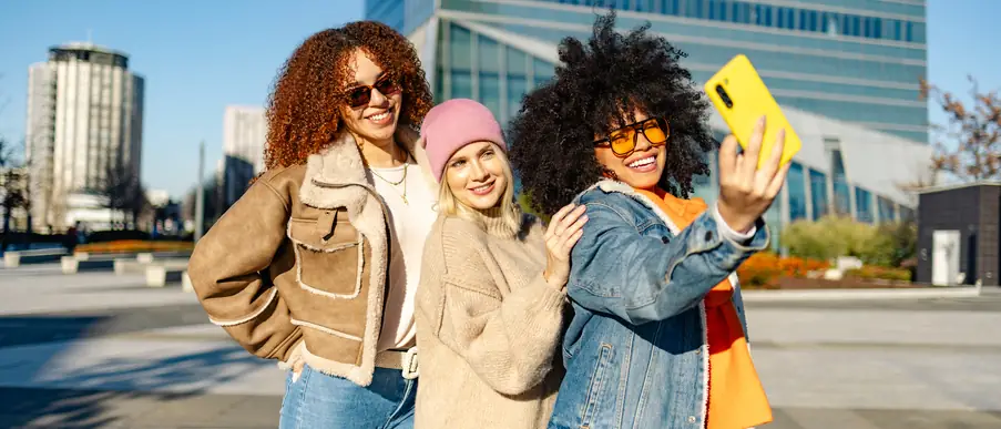 Bahnhöfe und Umfeld ganzheitlich entwickeln drei glückliche junge Frauen, die in der Stadt ein Selfie machen