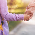 Schulkind hält Hand der Mutter, Nahaufnahme