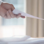 Hand reicht sitzenden Mann ein Blatt, eine Kündigung