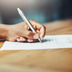 Frau füllt mit einem Kugelschreiber einen Fragebogen aus