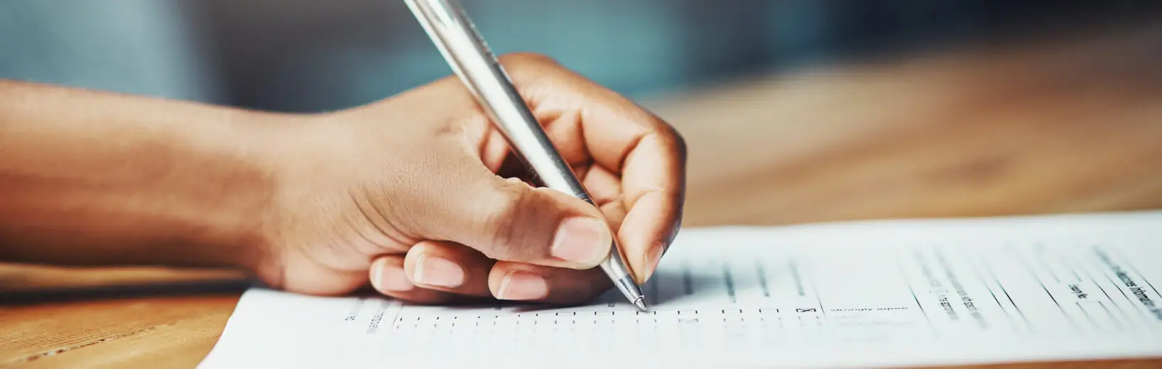 Wie Sie als Betriebsrat bei Mitarbeiterfragebögen mitbestimmen Frau füllt mit einem Kugelschreiber einen Fragebogen aus