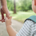 Kind und Mutter auf dem Schulweg, Nahaufnahme Hände