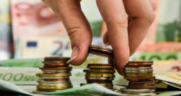 Großaufnahme von Euroscheinen und Münzen und Fingern, die sie stapeln