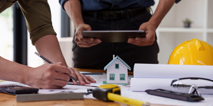 Entwürfe, Baupläne liegen auf Tisch, Architekt macht Notizen