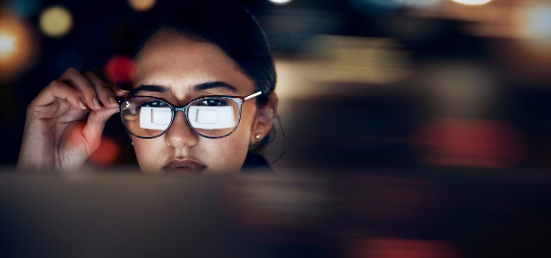 Frau mit Brille liest Text in Computer