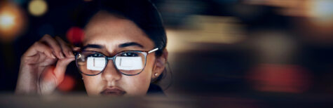 Frau mit Brille liest Text in Computer