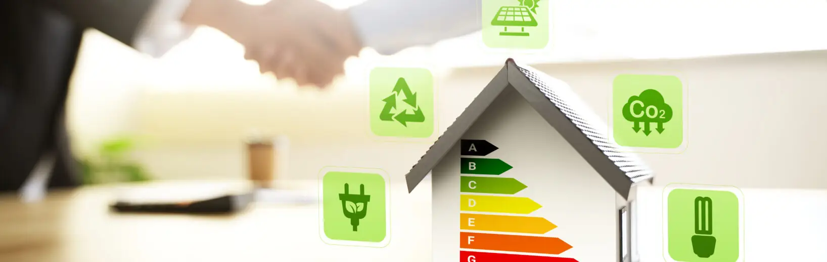 Gebäudemodernisierungsgesetz (GModG) 2026 in Kraft: Was sich für Architekten und Planer ändert Modellhaus mit Energieeffizienzskala von A bis G, umgeben von Symbolen für Photovoltaik, CO₂-Reduktion, Recycling und Energieeffizienz. Im unscharfen Hintergrund reichen sich zwei Personen die Hand – als Symbol für nachhaltiges und energieeffizientes Bauen und Modernisieren.
